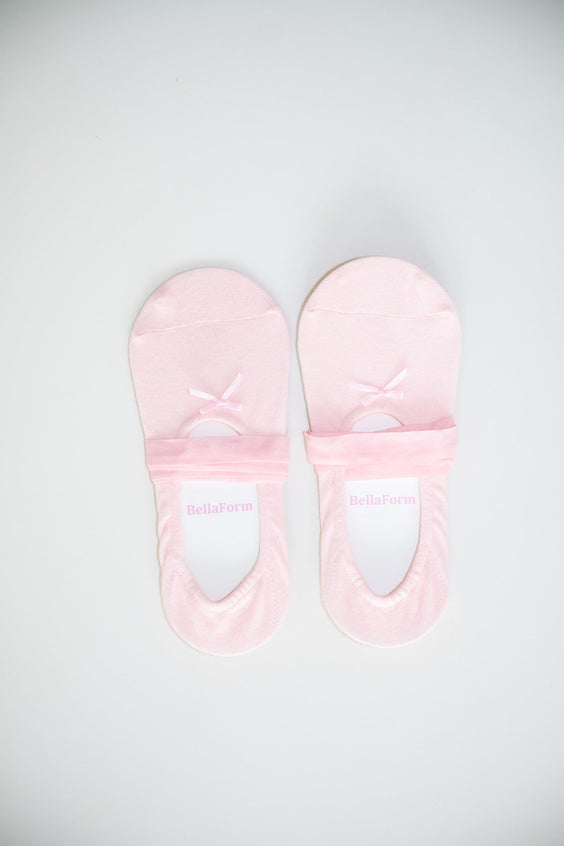 A pair of BellaForm ballet-laced grip socks in Ballet Pink, laid flat on a pale background with satin ribbons wrapped around the arch.